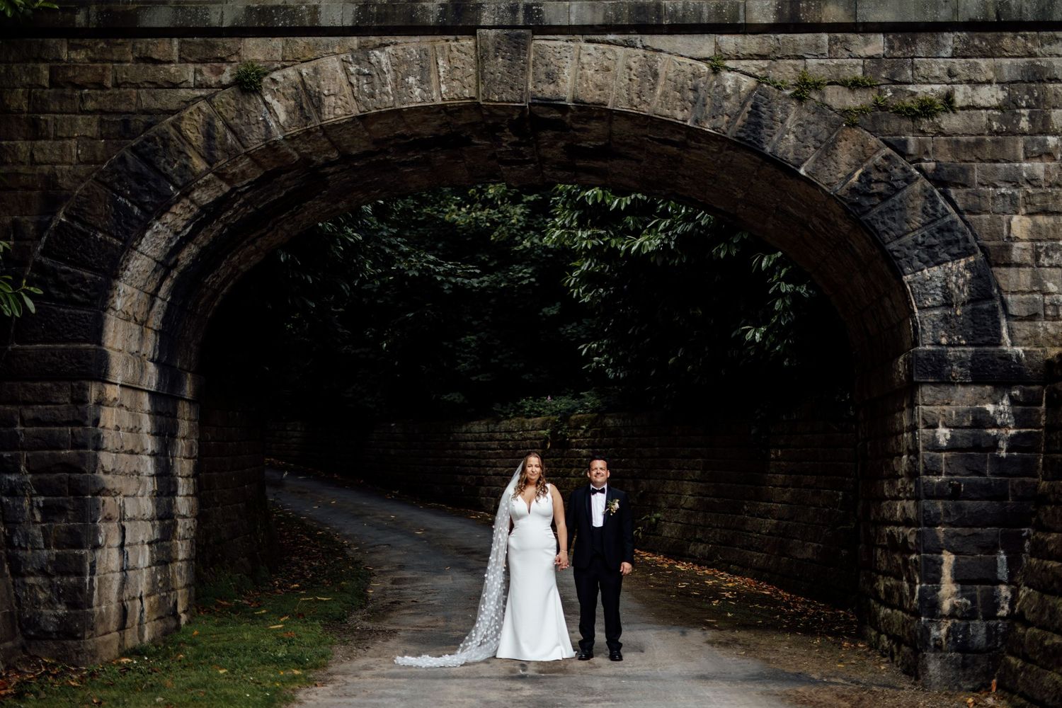 Stone archways and paths create a dramatic backdrop for wedding photography at a historic venue.