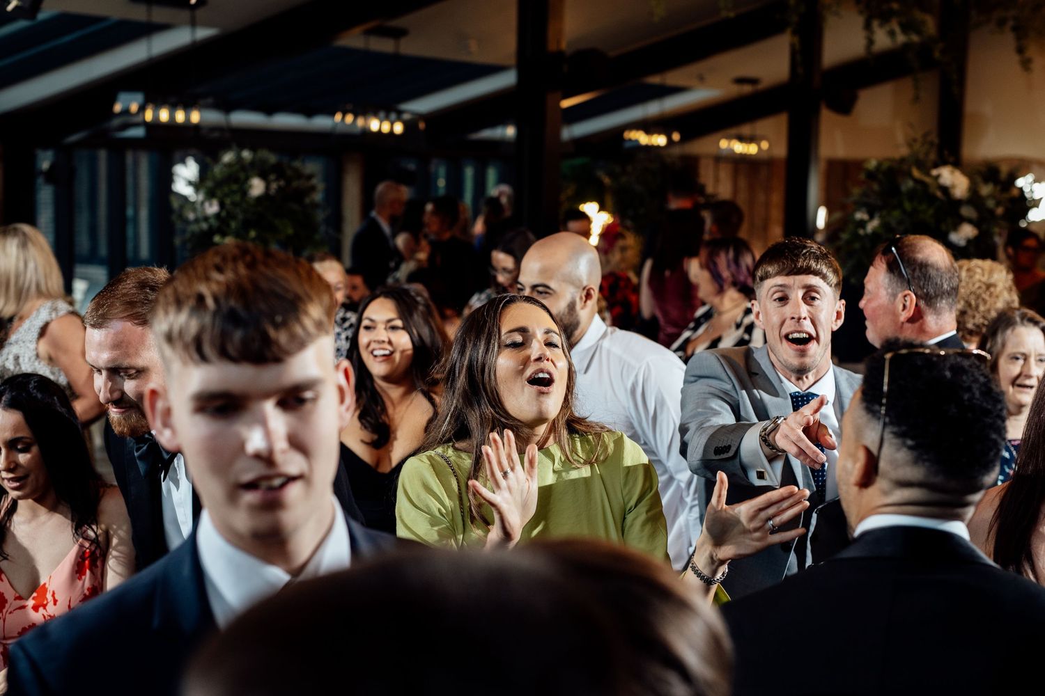Lively crowd of wedding guests dancing and celebrating on the dance floor.