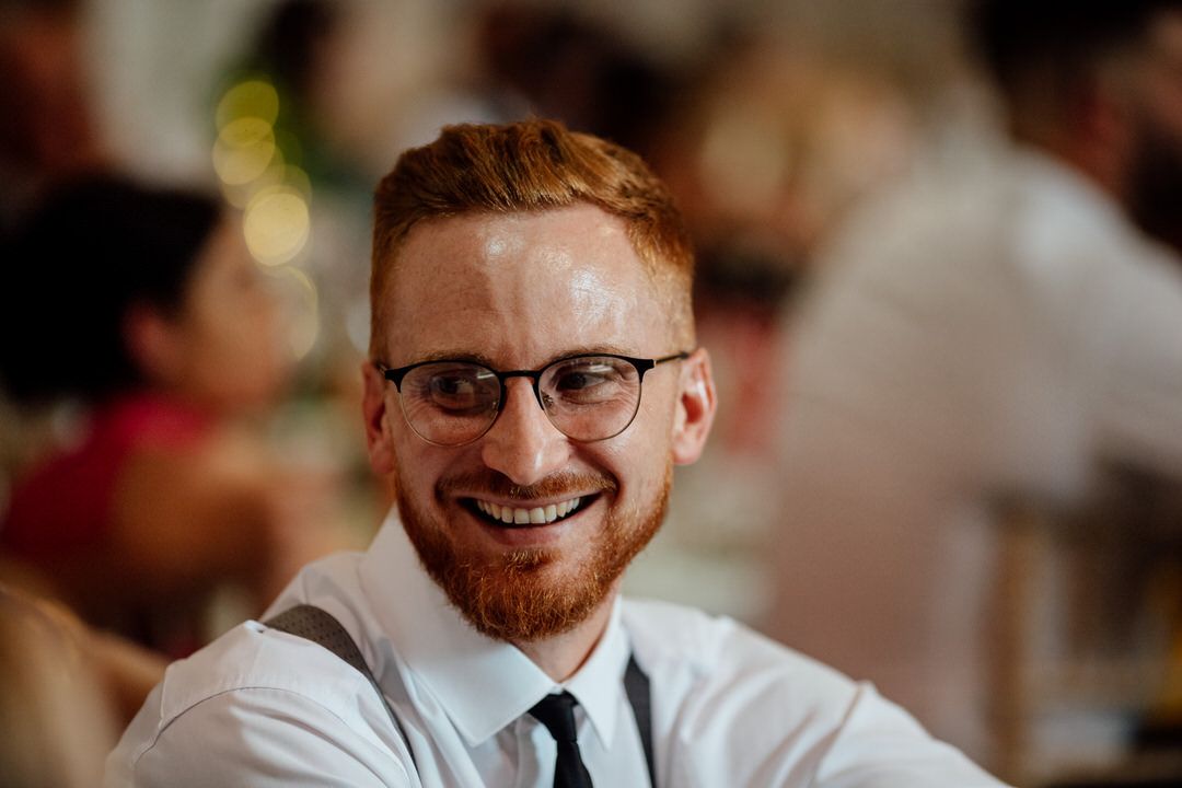 Guests share joyful reactions during wedding reception speeches.