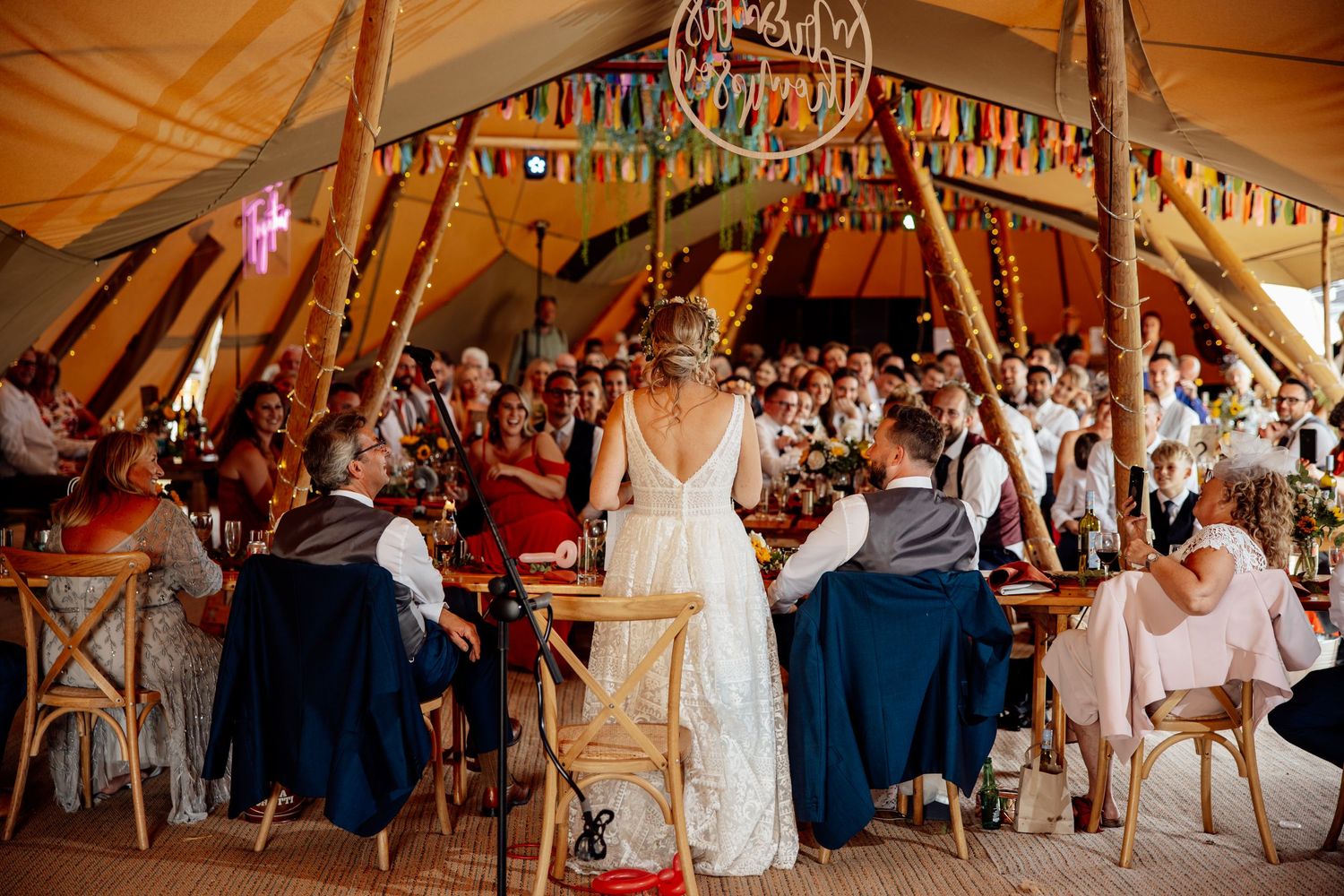 A festive celebration inside a large decorated tent with string lights and bunting.