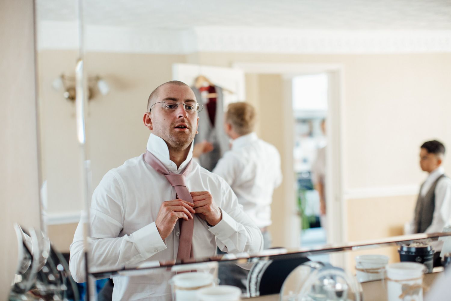 Men in formal attire preparing in bright indoor setting.