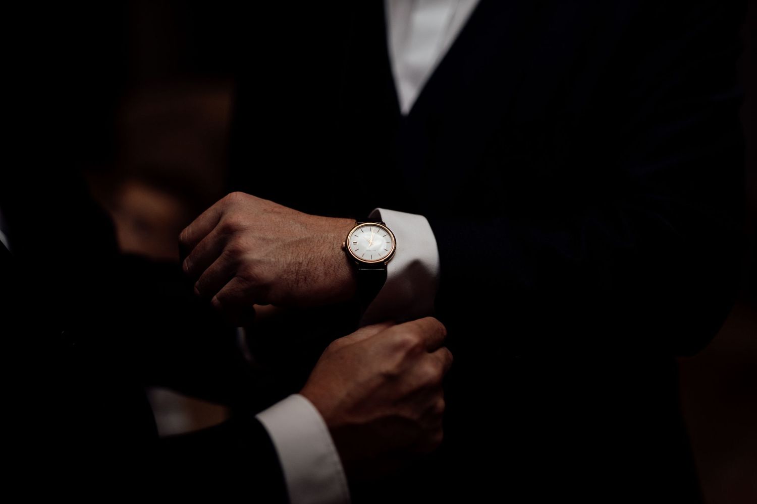 Close-up details of formal attire and accessories being adjusted during a wedding preparation.