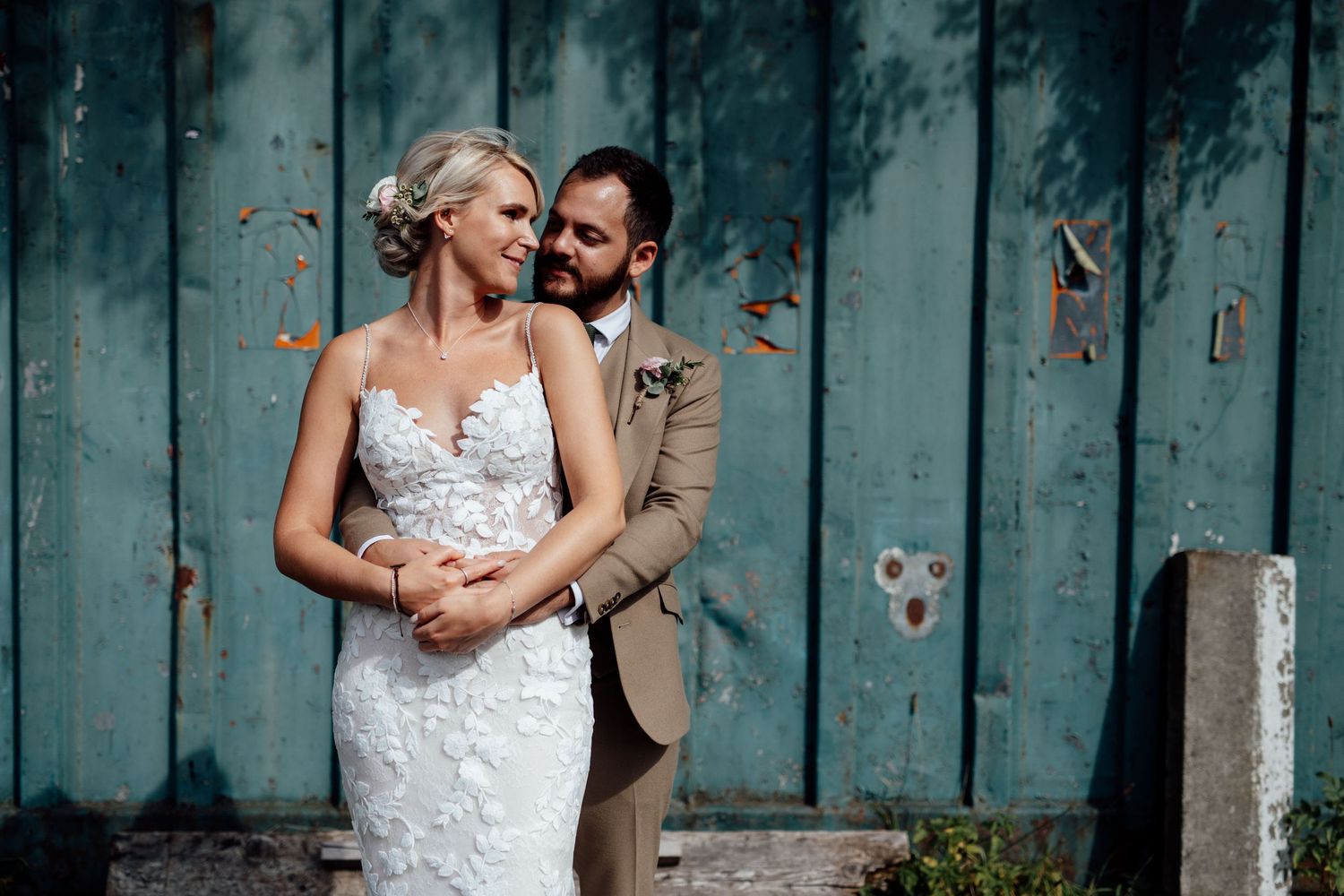 A romantic moment captured against a weathered blue-green wooden wall backdrop.