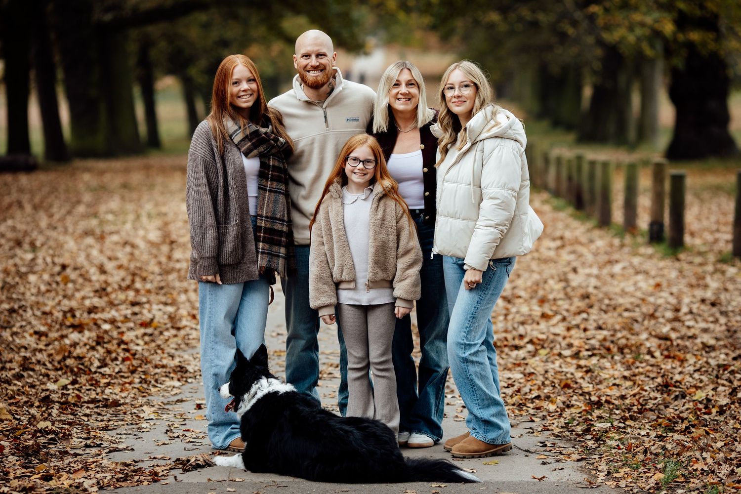 Group sitting together on fallen leaves during golden hour photo session.