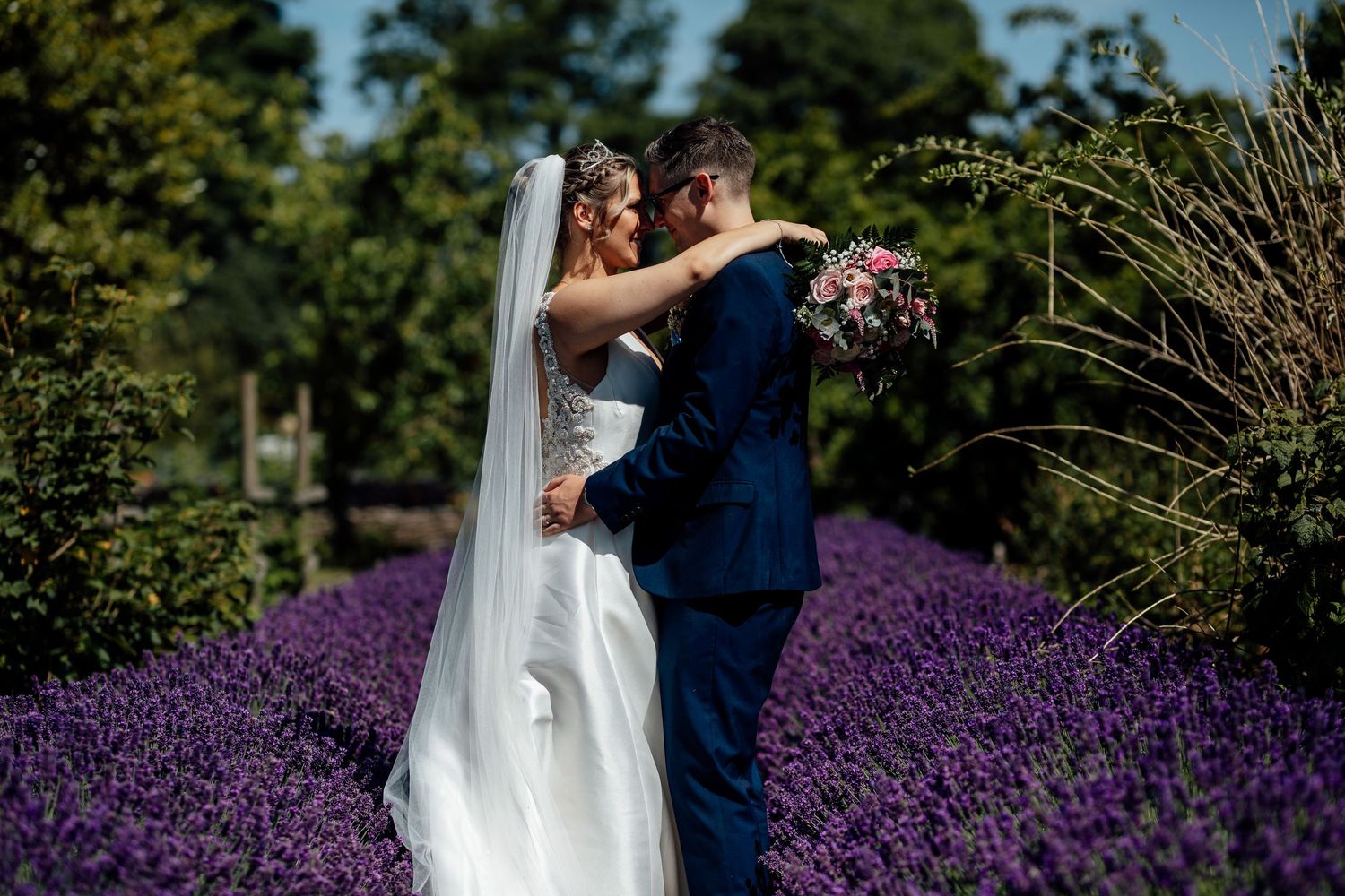 A couple shares a romantic moment in a blooming lavender field on their wedding day.