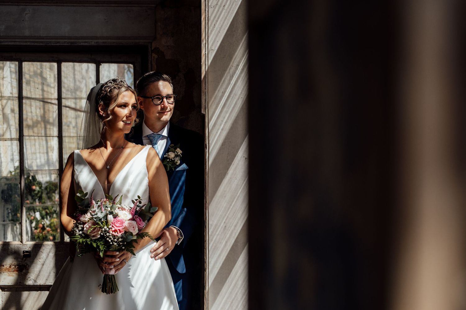 Wedding portraits captured through window panes with dramatic lighting and shadows.