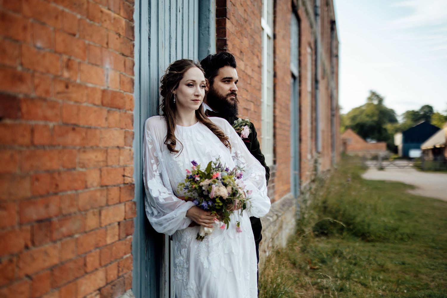 Rustic brick wall and blue door provide romantic backdrop for wedding portraits.