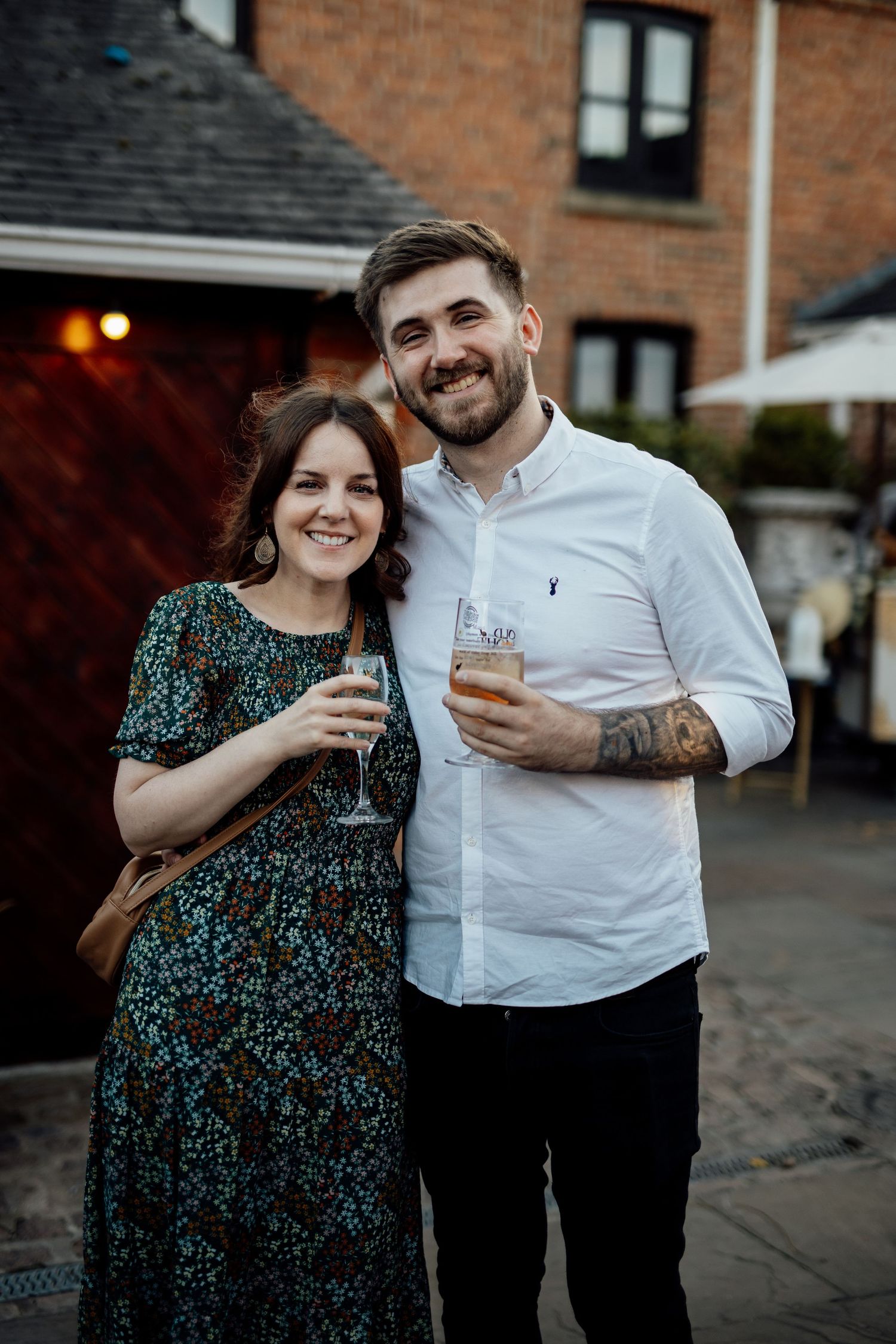 Couple enjoying champagne together outside a brick building at dusk.