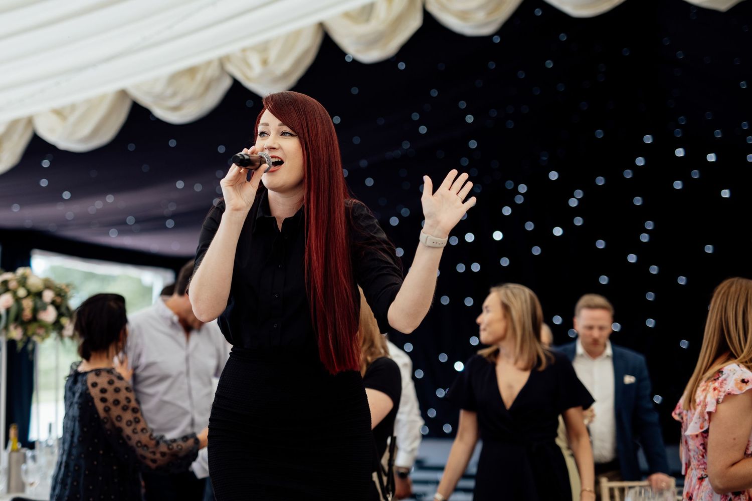 Live band performing under white tent at evening reception.