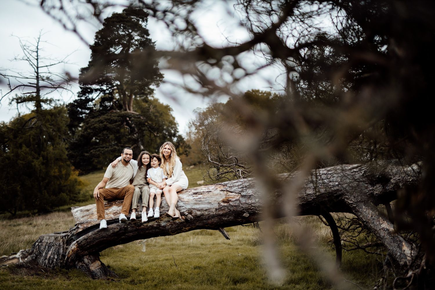 A family relaxes on fallen logs during a rustic outdoor photography session.
