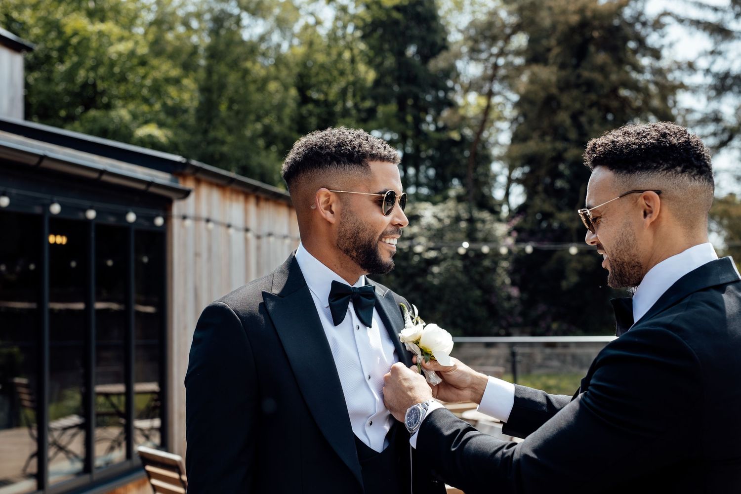 Groomsmen sharing a casual moment outdoors in formal attire.