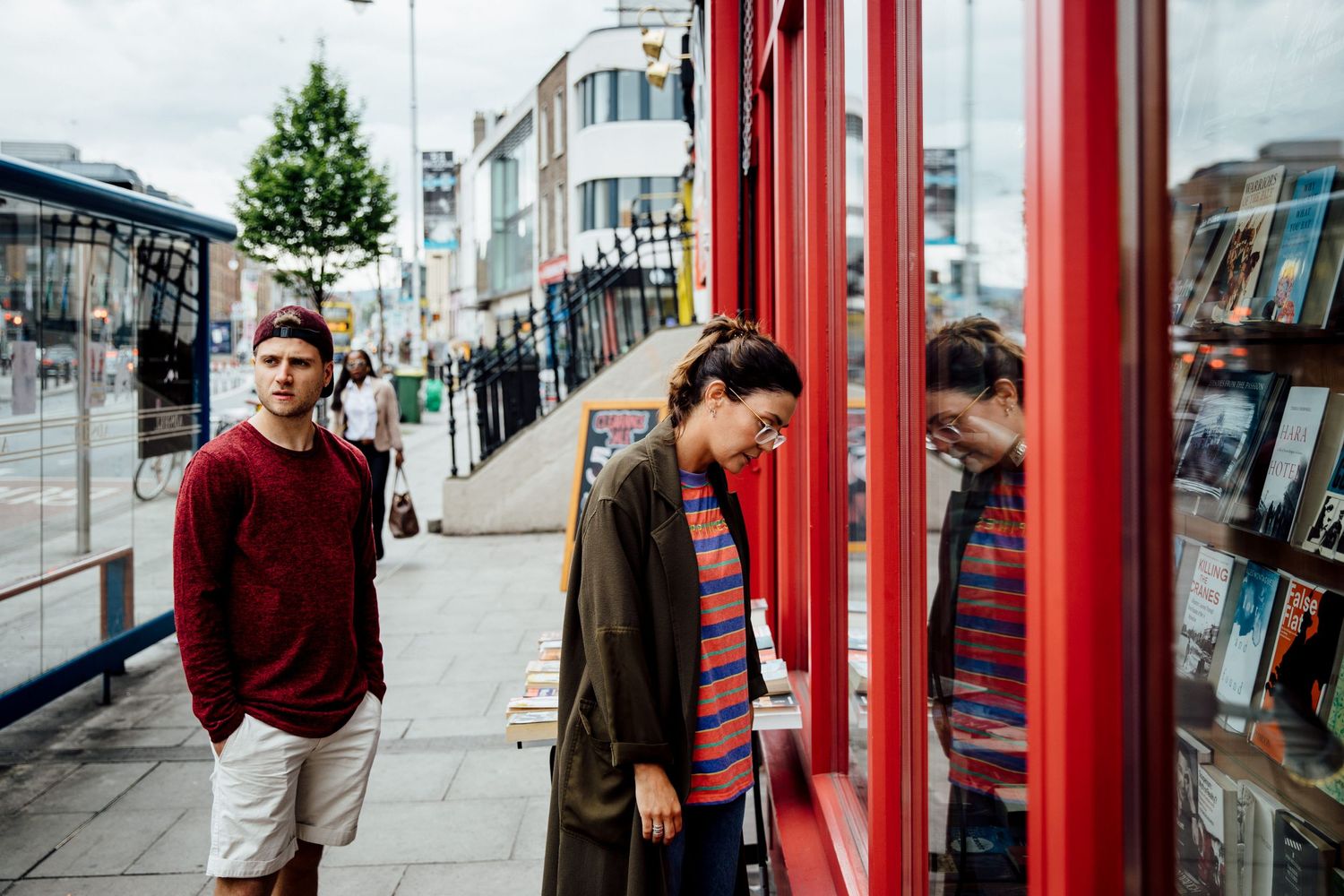 Series of romantic interactions captured through red phone booth frames on a city street.