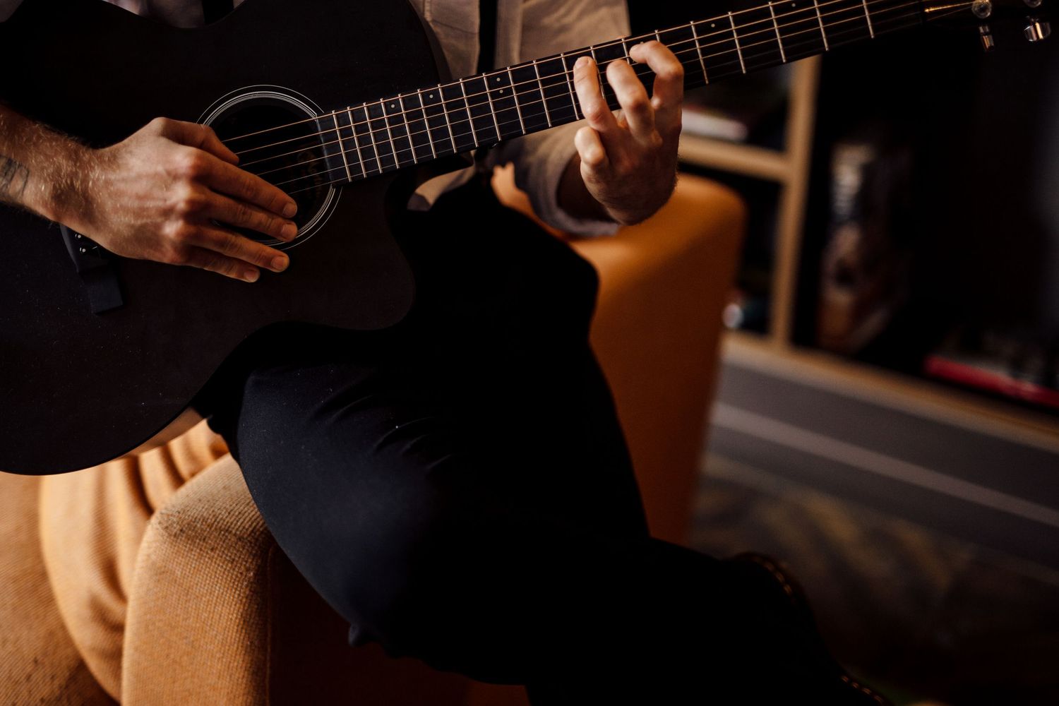 Close-up shot of hands playing an acoustic guitar in warm lighting.