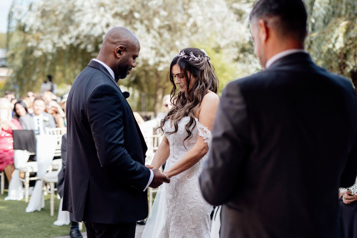 Wedding ceremony guests gather on manicured lawn for outdoor celebration.