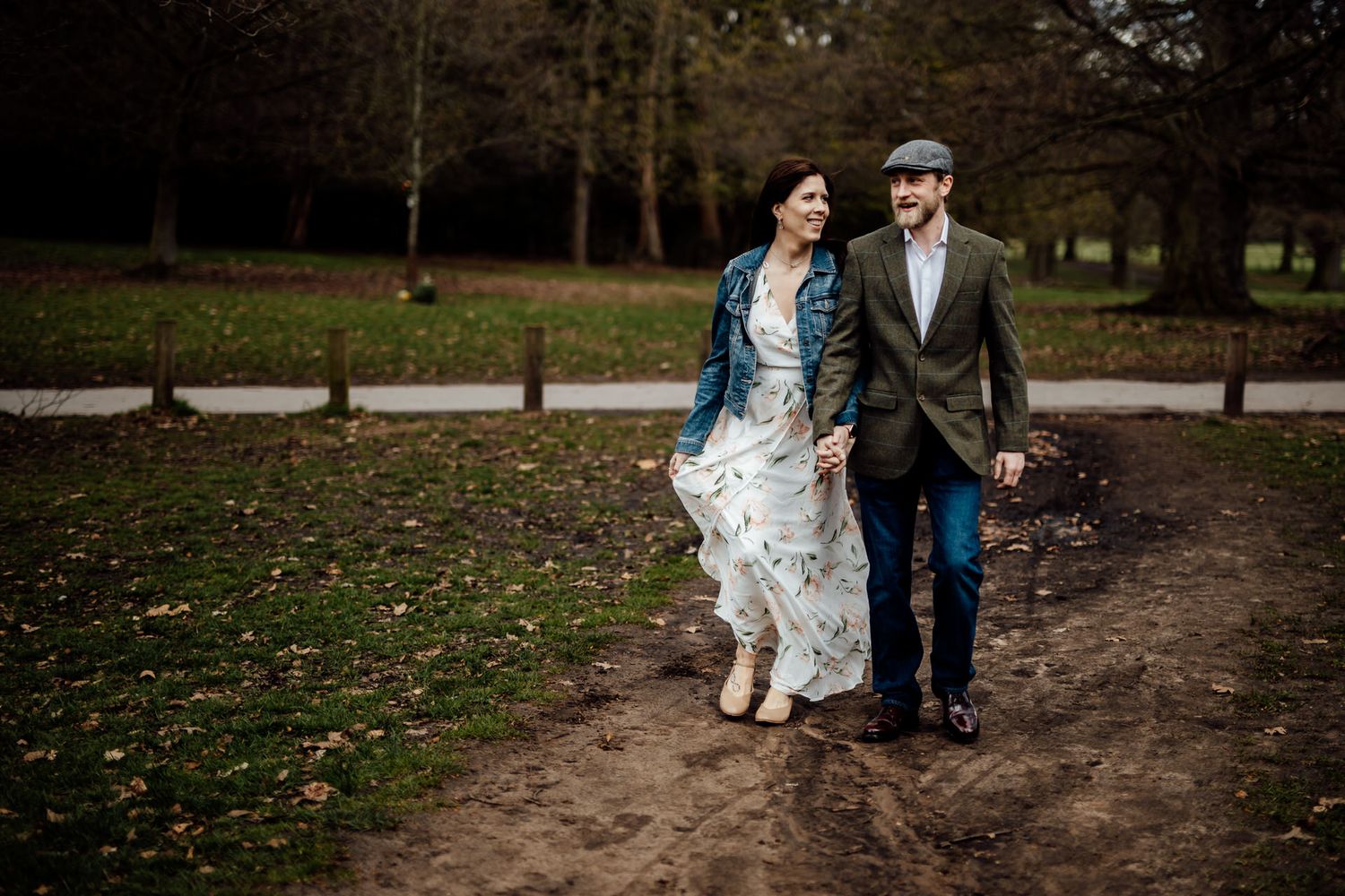 Couple walking together on autumn path through park grounds.