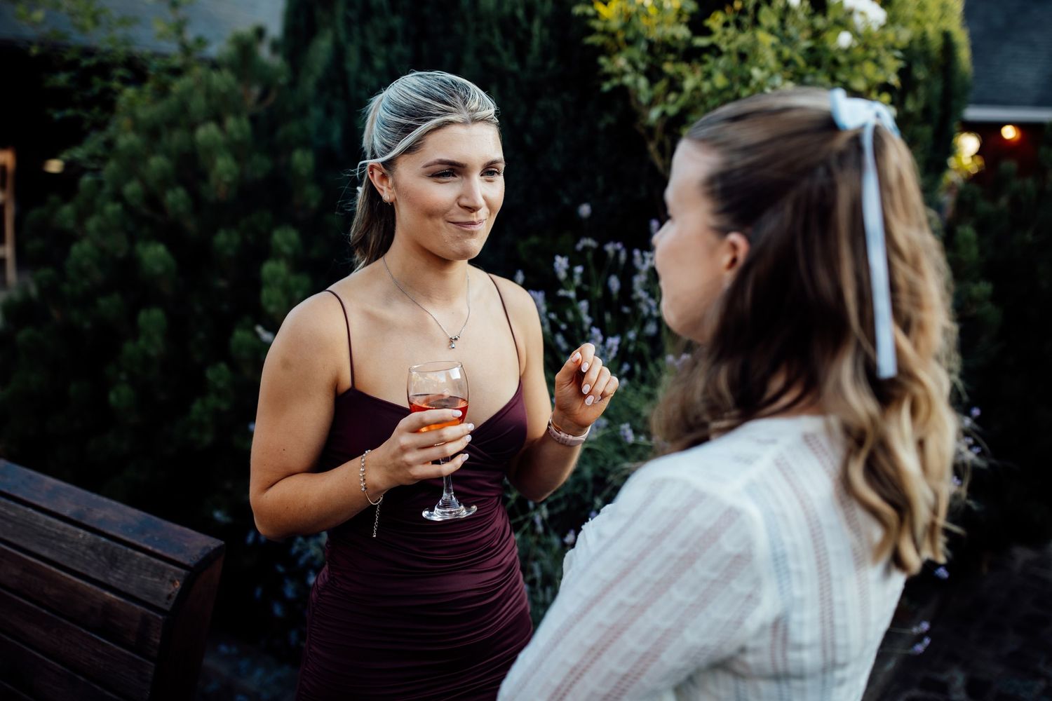 Guests mingling at an outdoor wedding reception with greenery in the background.