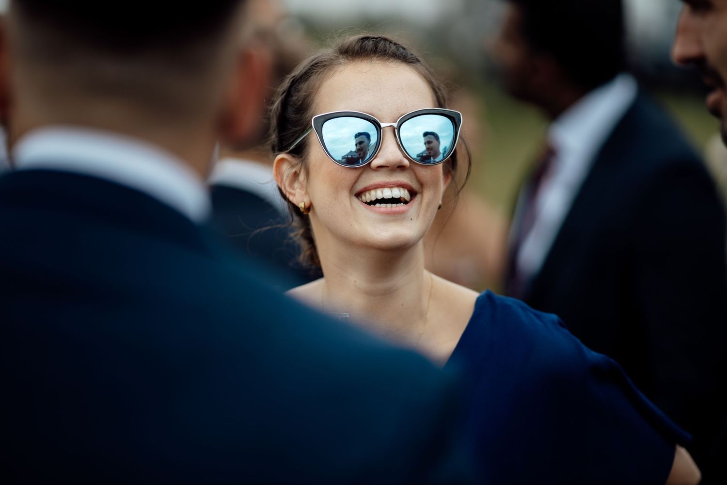 Guest in sunglasses smiling during outdoor event with reflective lenses.
