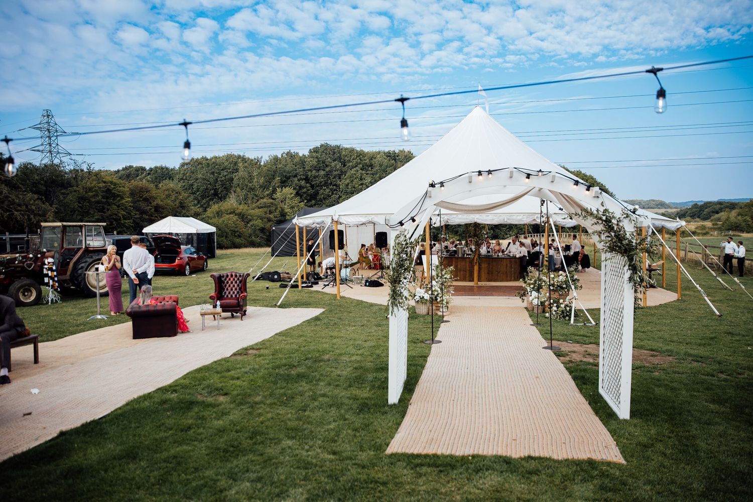 Outdoor wedding venue with white tent and archway decorated for ceremony.