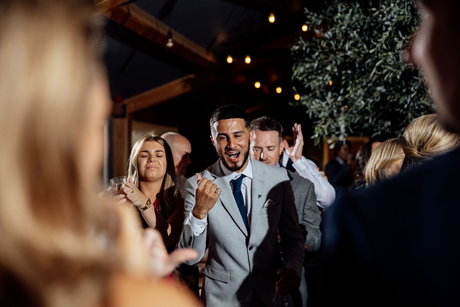 Evening wedding reception with guests celebrating under ambient lighting.