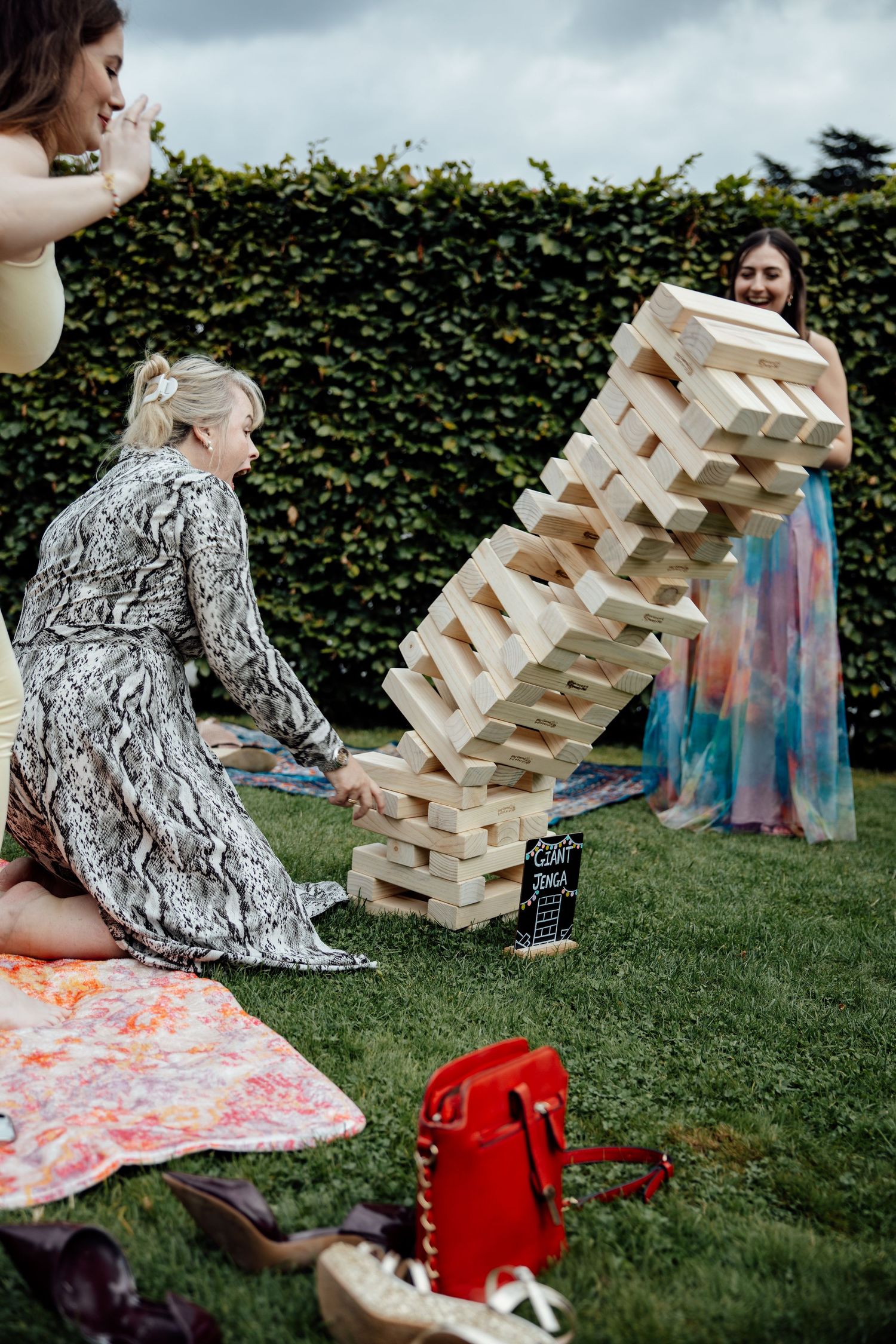 Giant Jenga game set up on grass during outdoor wedding reception.
