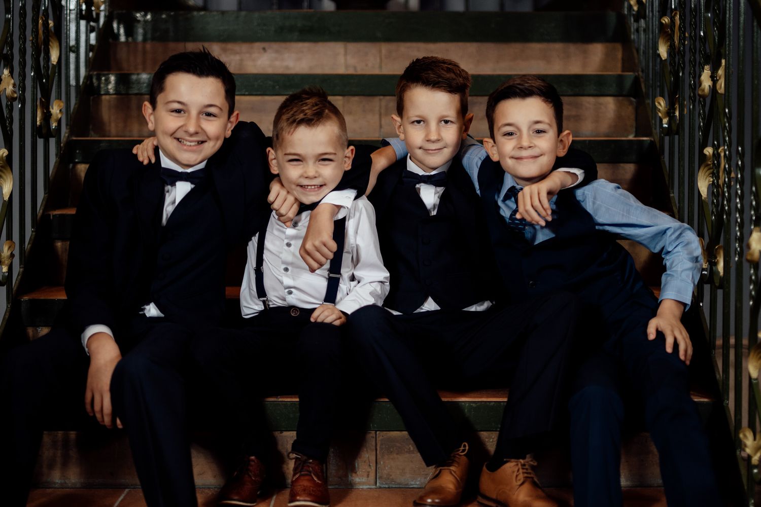 Young attendants in formal attire seated on an elegant dark bench.