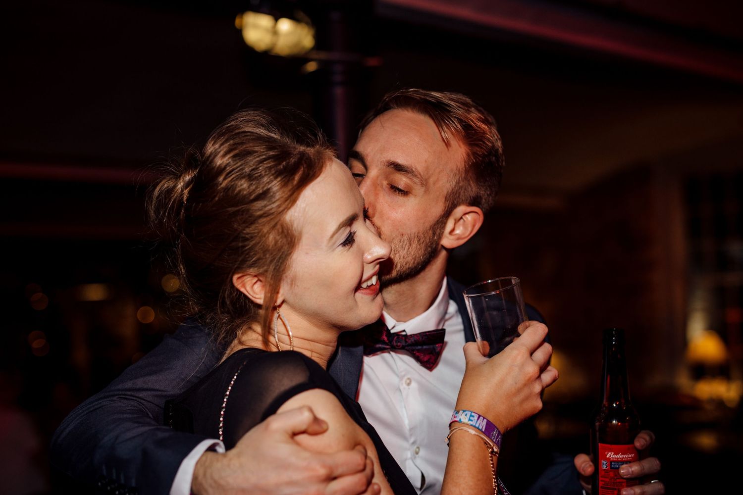 Couple sharing an intimate dance moment at a dimly lit wedding reception.