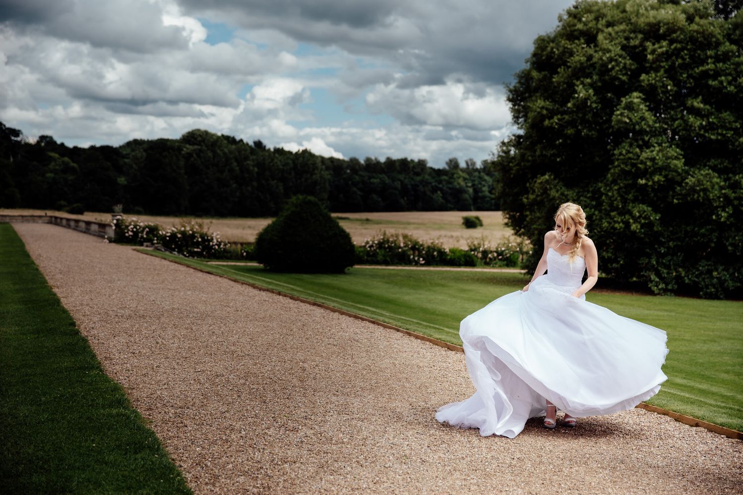 Wedding venue grounds with dramatic cloudy sky and long gravel driveway.