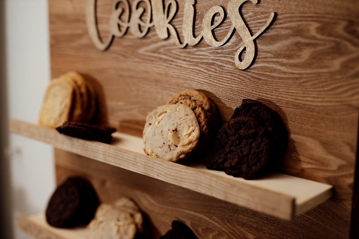 Rustic wooden shelves displaying cookies and baked treats in a warm, cozy setting.