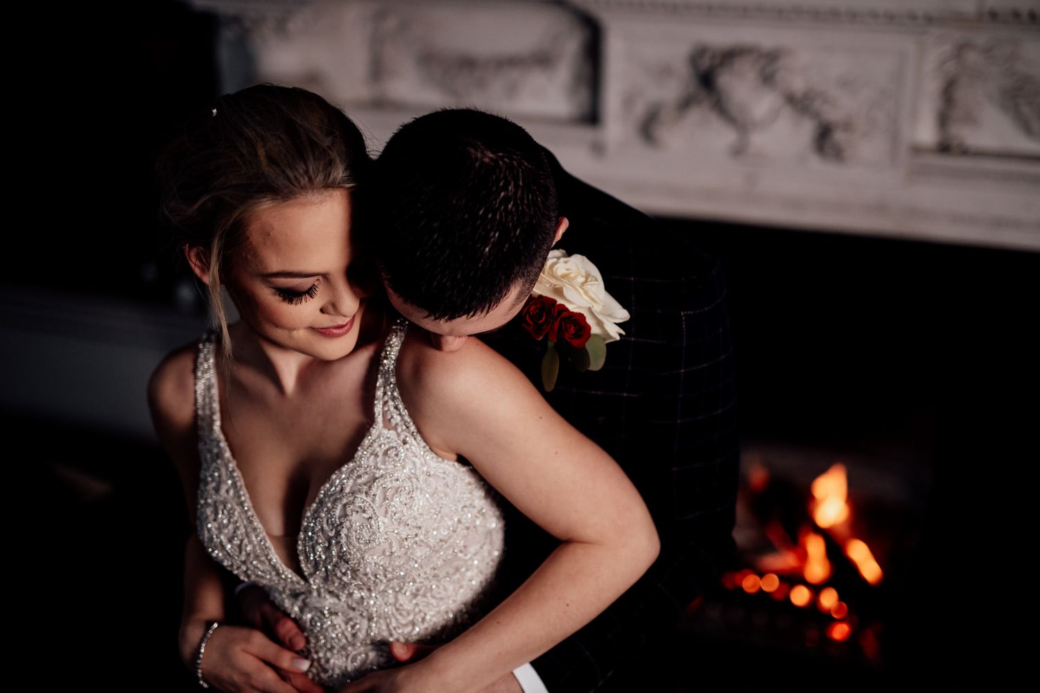 A romantic moment by the fireplace with a bride in an elegant lace wedding dress.