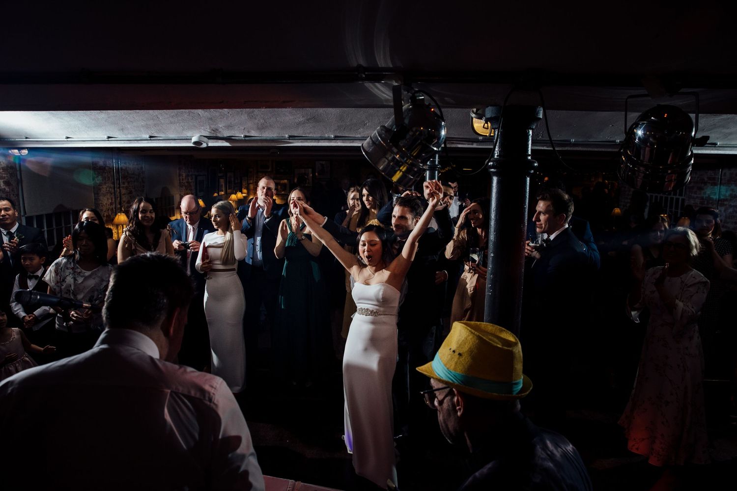 Silhouettes of wedding guests dancing and celebrating on a dark dance floor.