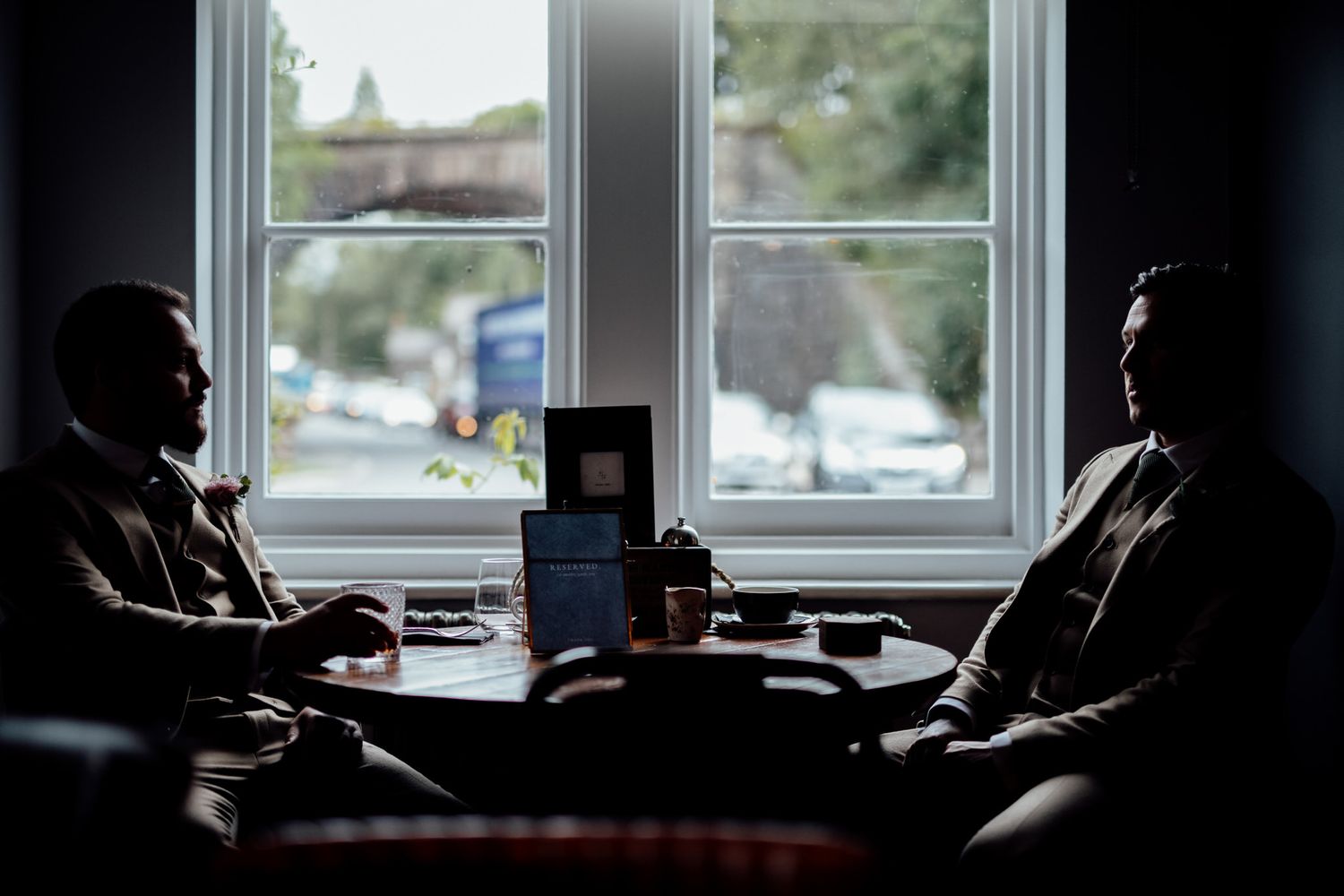 Silhouetted figures by window with natural backlighting creating dramatic shadows.