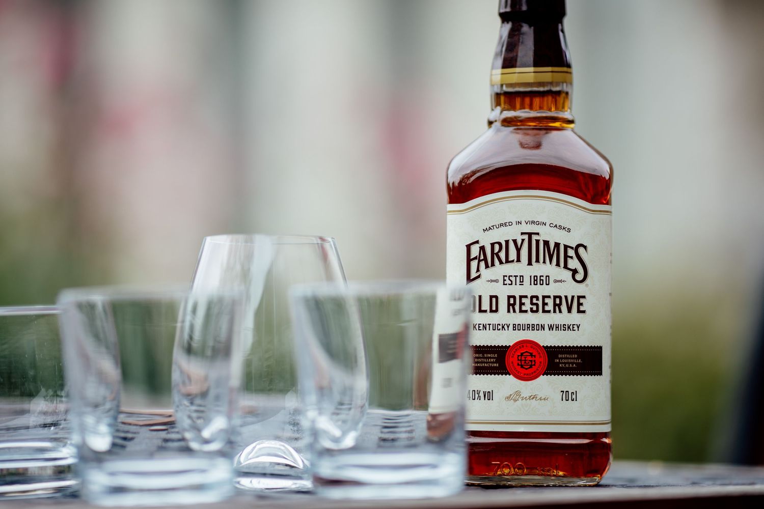 A bottle of Early Times bourbon whiskey with empty glasses set for service.