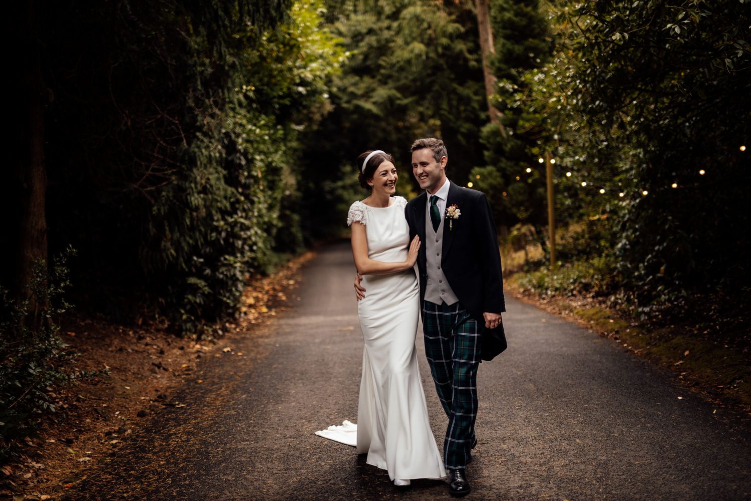 Candid wedding moments captured on a tree-lined pathway in natural lighting.