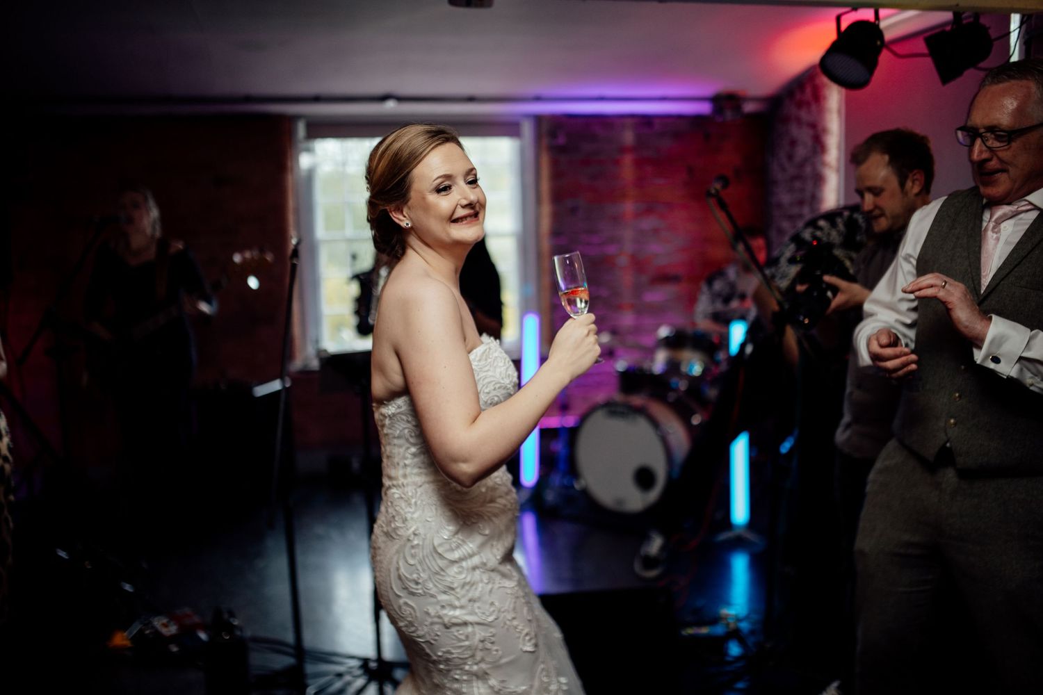 Wedding reception dance floor with colorful lighting and guests celebrating.