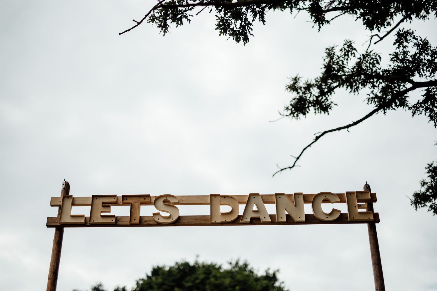 Wooden barn venue signage and entrance surrounded by trees and natural scenery.