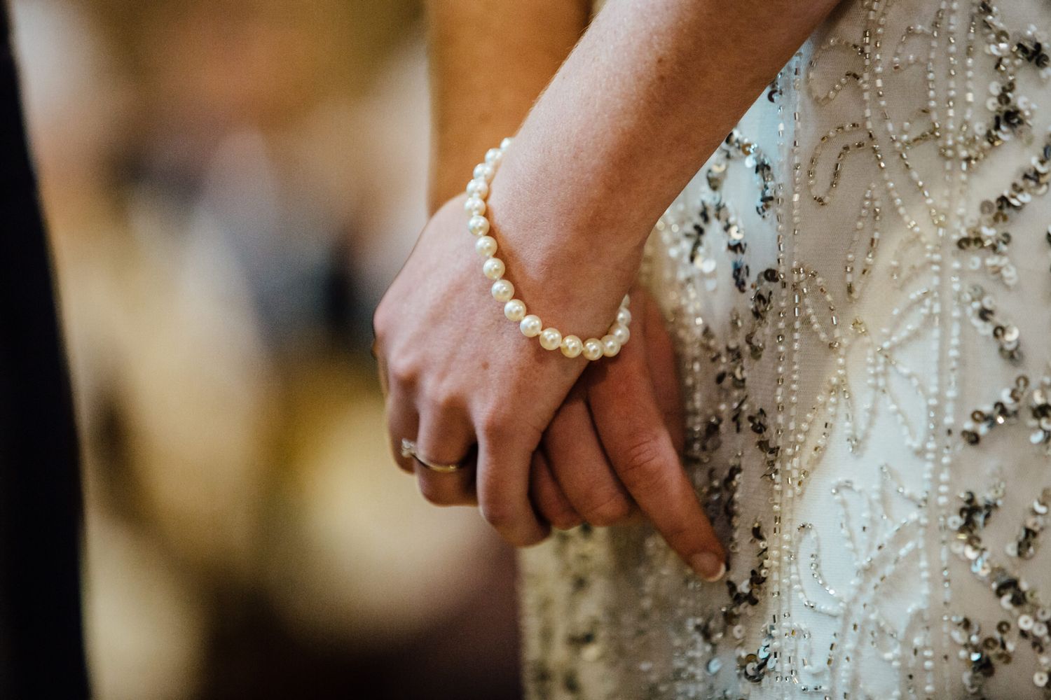 Detailed shot of lace wedding dress with pearl accents.