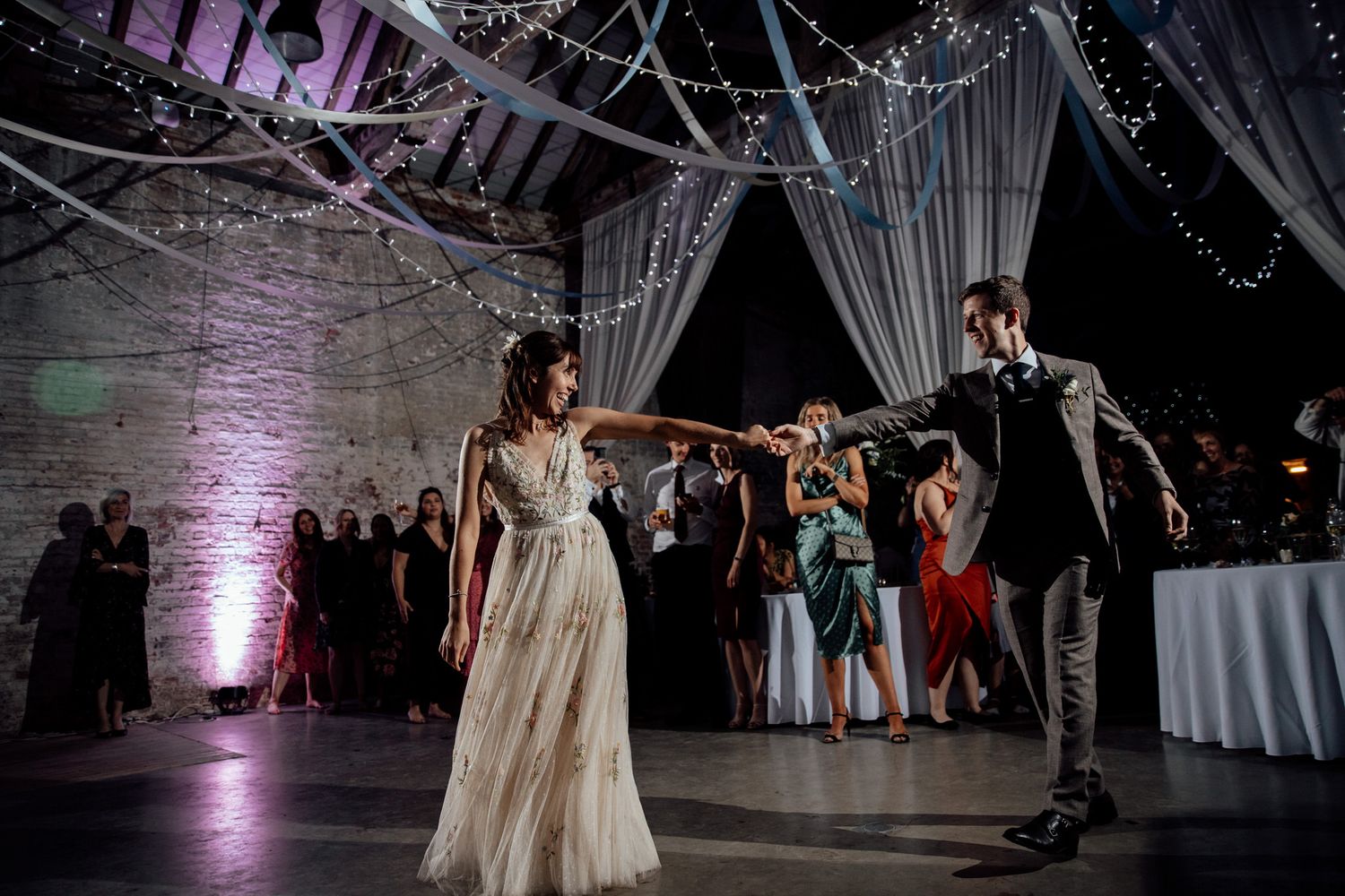 Wedding reception dance floor with dramatic lighting and white drapes creating an enchanting atmosphere.