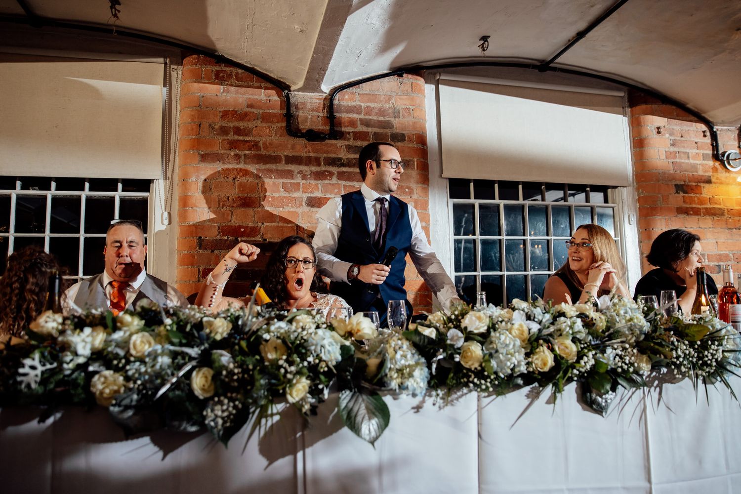 Elegant head table decorated with lush greenery garland and white floral arrangements.
