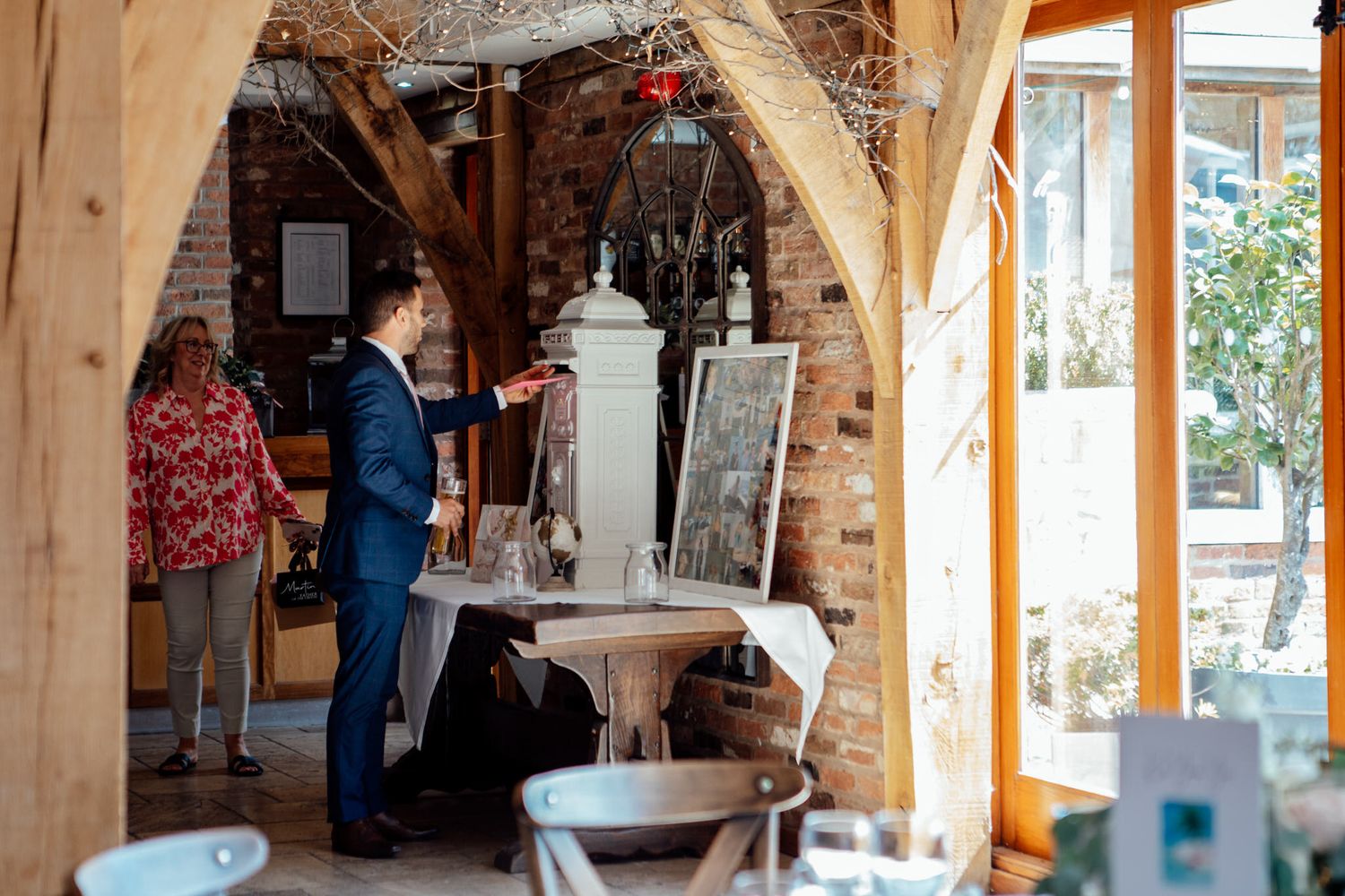 Interior of a rustic barn venue with exposed wooden beams and natural lighting.