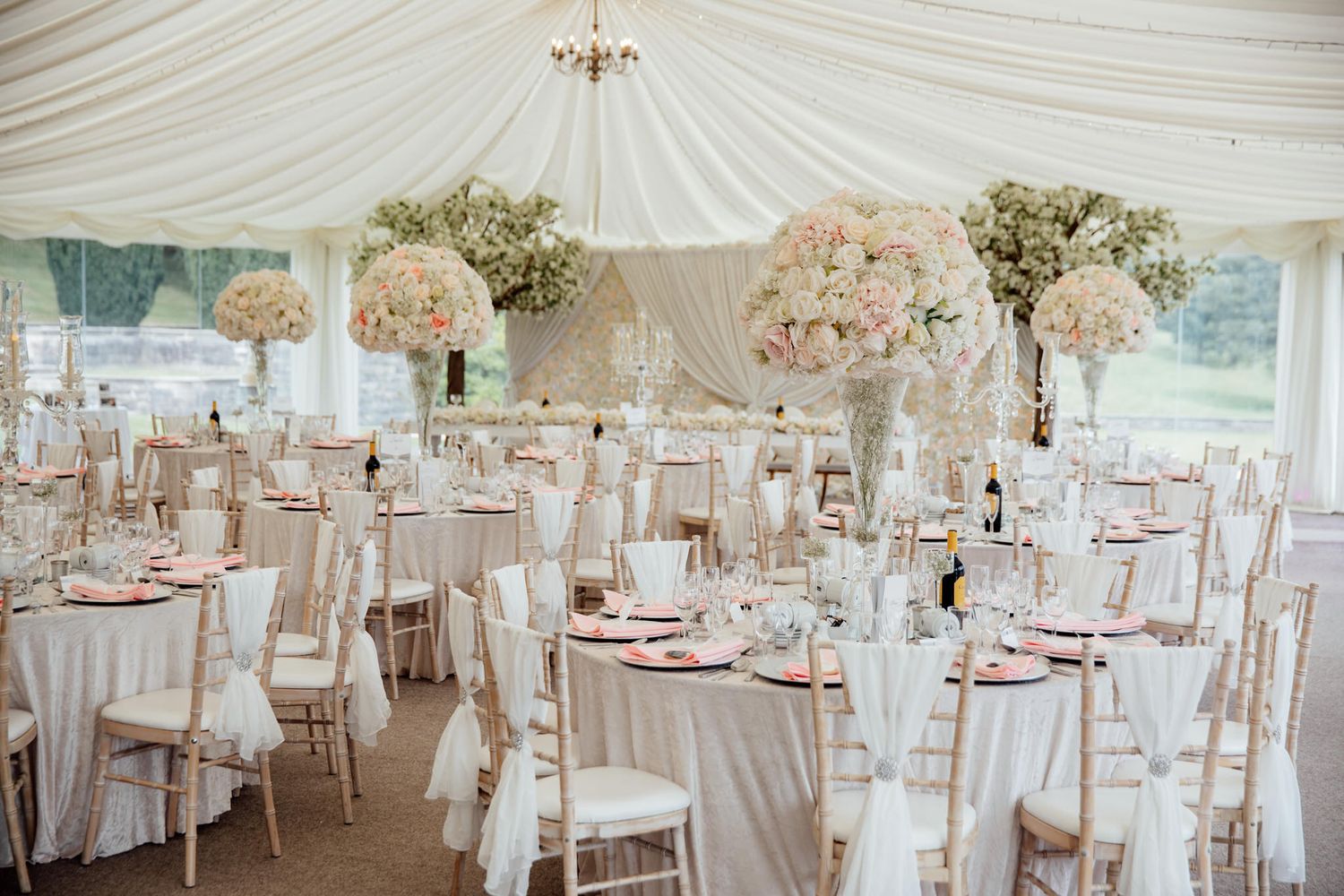 Elegant wedding reception setup with white draped ceiling and floral centerpieces.
