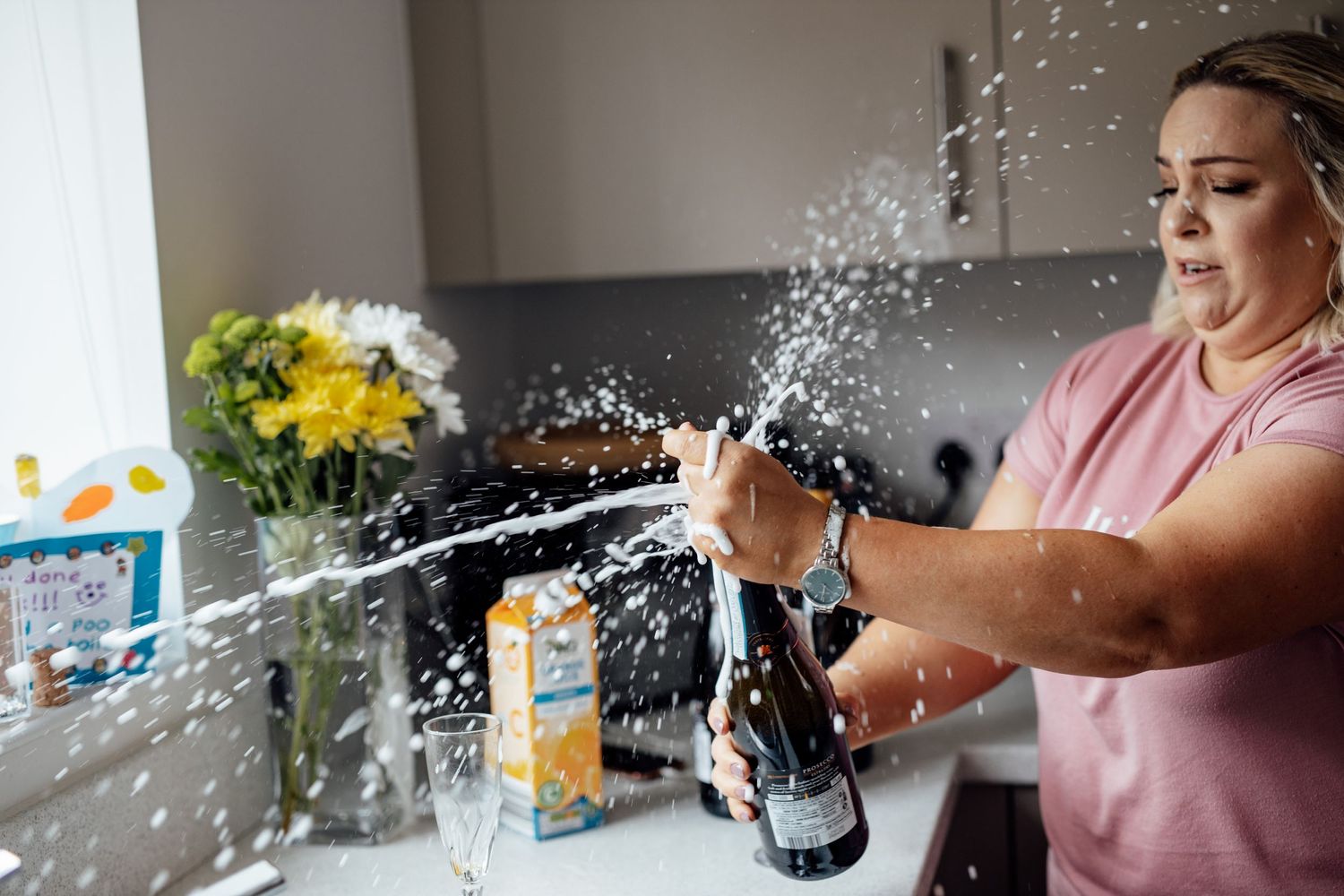 A celebratory moment with champagne spraying in a modern kitchen with yellow flowers.
