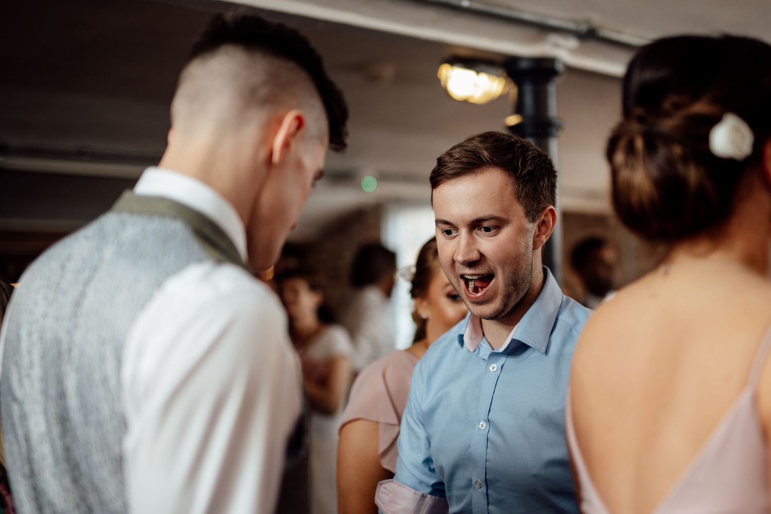 Wedding guests mingle and socialize during an indoor reception celebration.