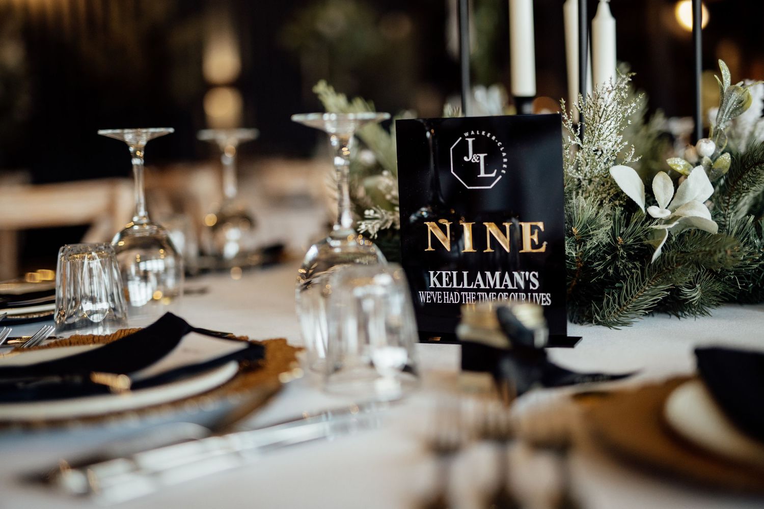 Modern black table numbers and delicate floral centerpieces adorn an elegant wedding reception table setting.