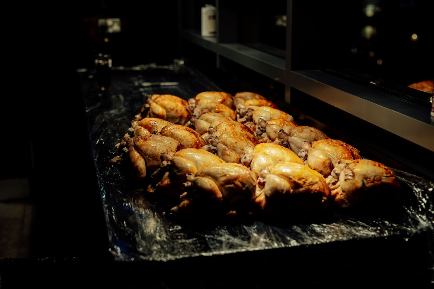 Grilled chicken pieces cooking on foil-lined grill at wedding reception.