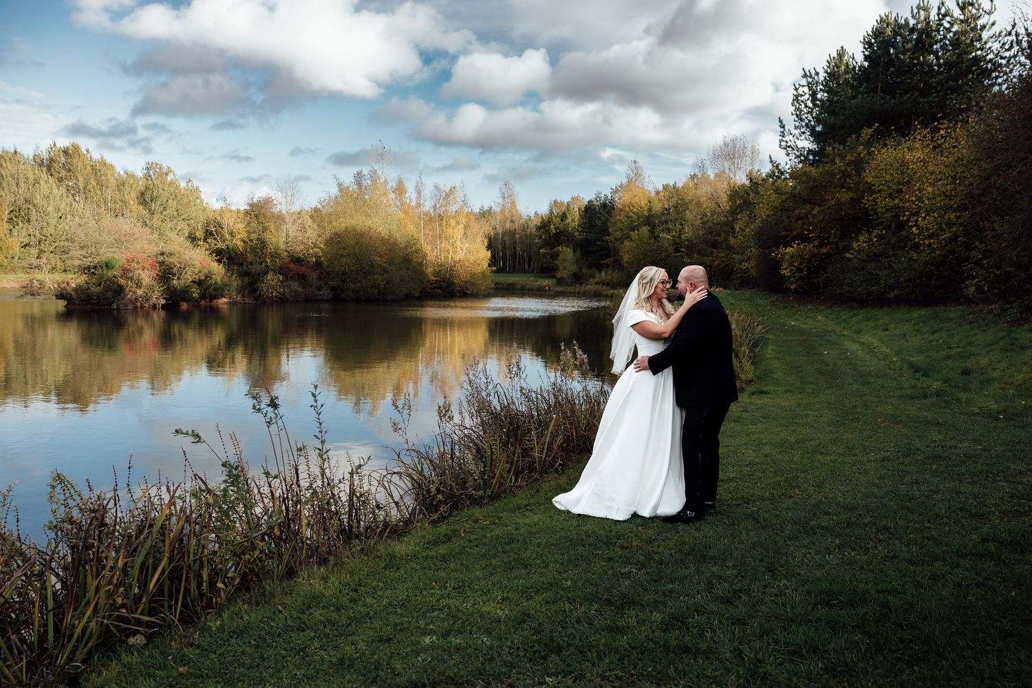 Scenic lakeside wedding photos with autumn trees and reflective water.