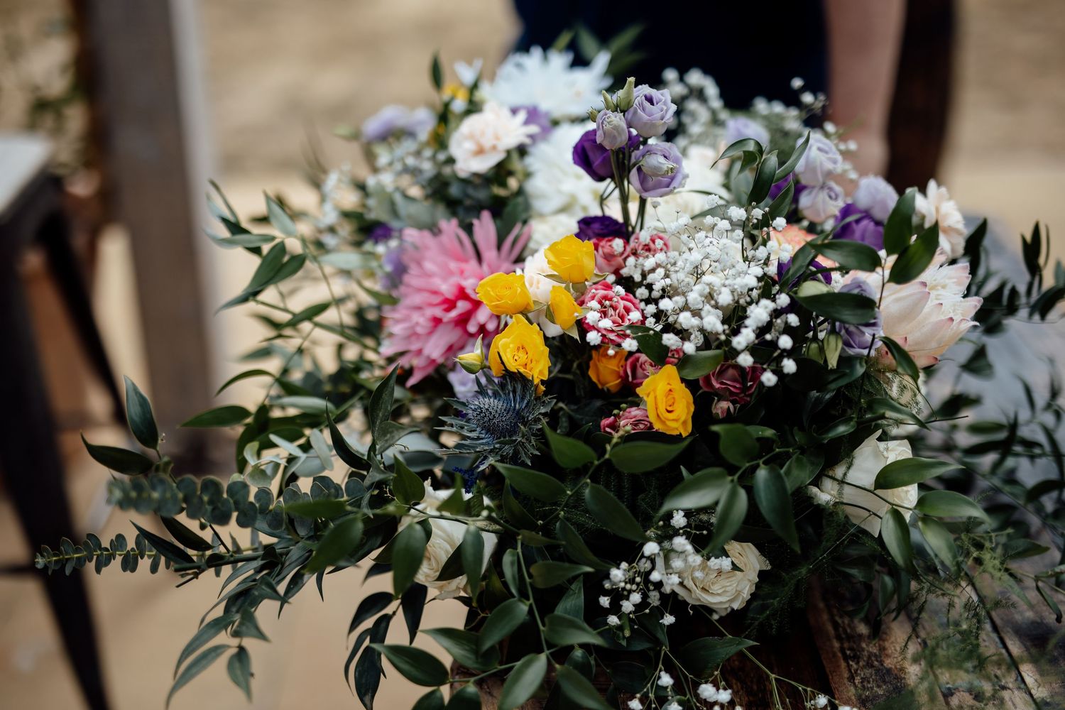 Colorful wedding bouquet with yellow, pink, purple flowers and eucalyptus greenery.