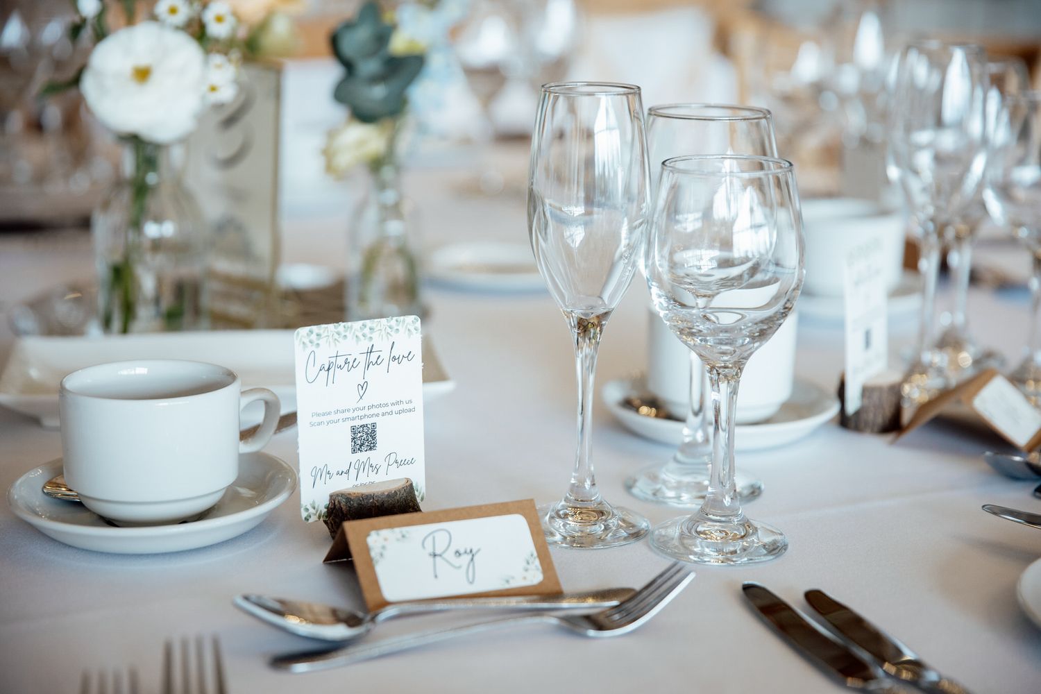 Elegant wedding reception table settings with wine glasses and place cards.