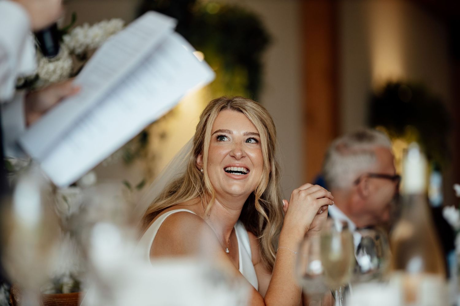 Guests share joyful reactions during emotional wedding reception speeches.