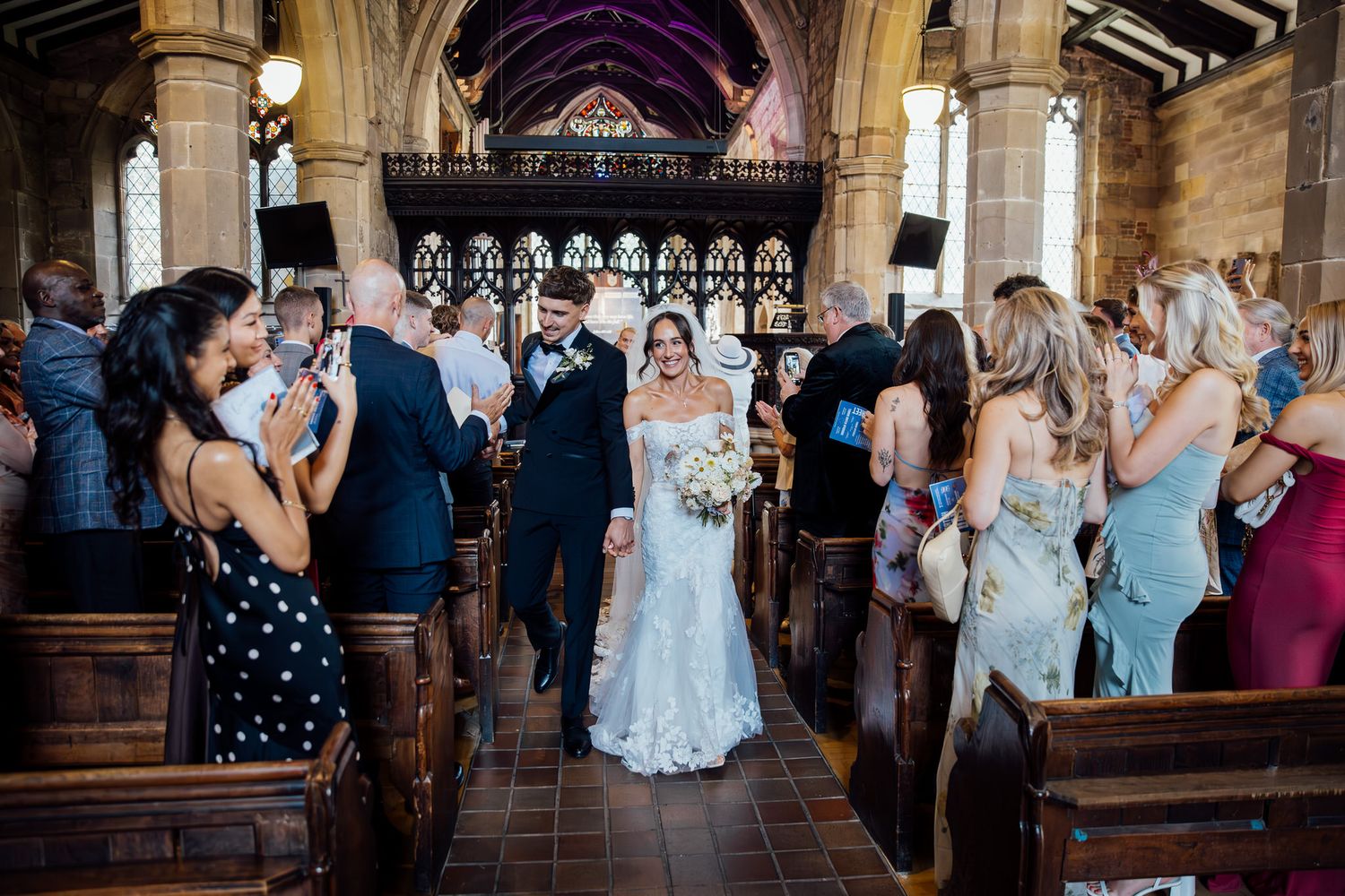Wedding ceremony in progress inside a traditional gothic church with wooden pews.