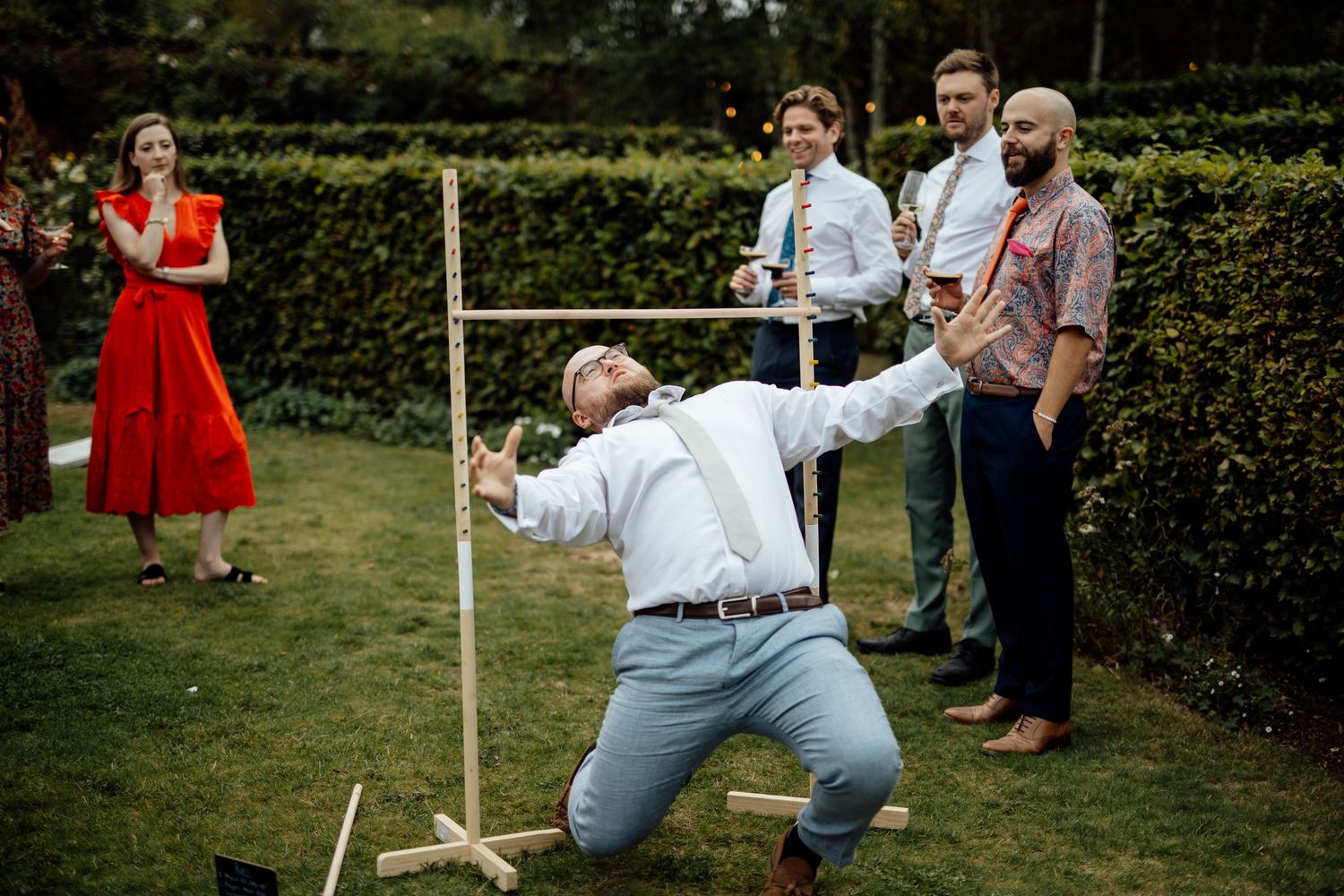 Wedding party plays lawn games during an outdoor garden reception.